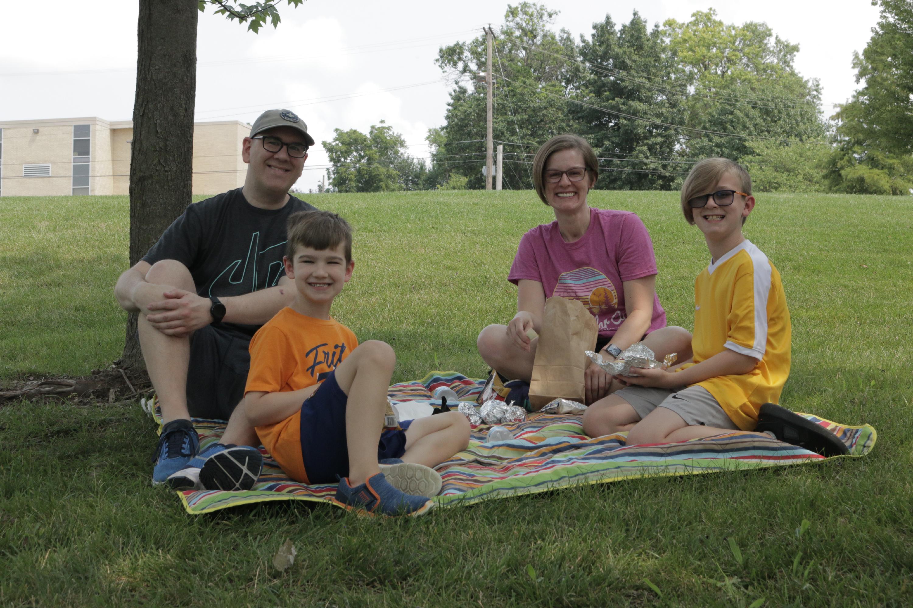 family eating hot dogs in park
